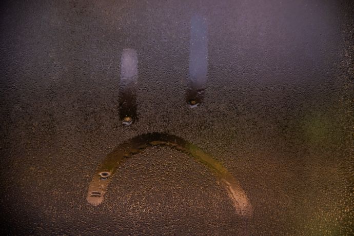 Condens op het raam met een verdrietige smiley op getekend. 